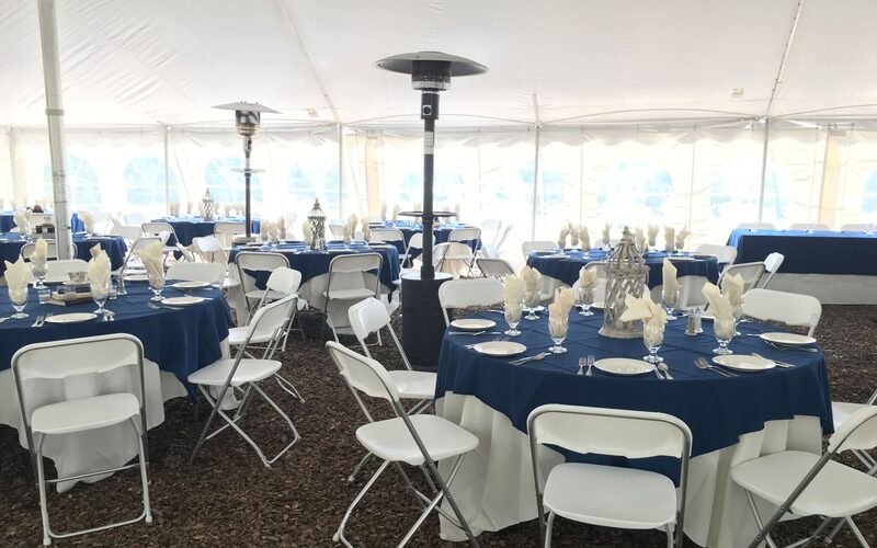 Tent reception setup with round tables, white chairs, blue linens, and heaters — General Rental event install